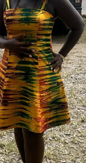After. Torso photographs of a client, cropped below the chin: in a tan pyjama-style set outdoors by a market stall, and in a yellow and green patterned dress outdoors.